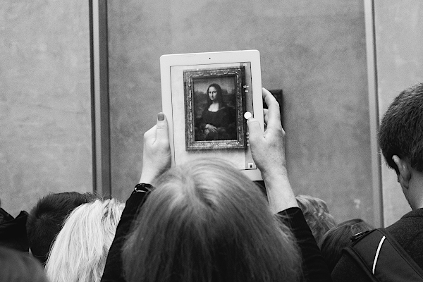 A person taking a photo using a tablet of the Monalisa painting