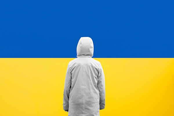 A person standing in front of Ukraine flag