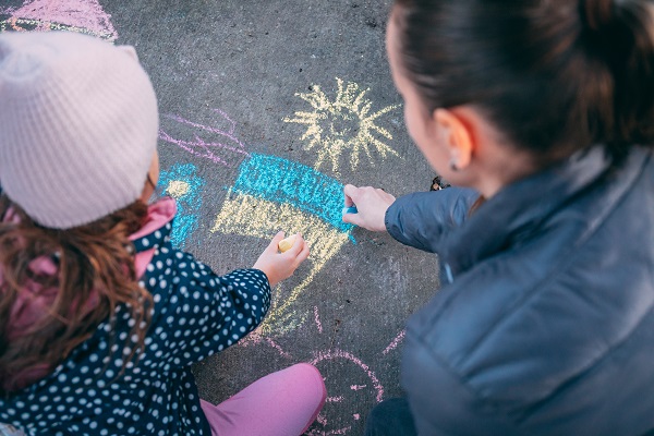 child draws Ukraine flag with chalk