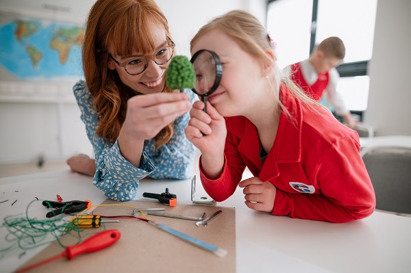 A teacher and a special needs pupil with a magnifying glass