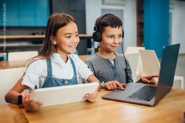 Two children studying using a laptop and a tablet