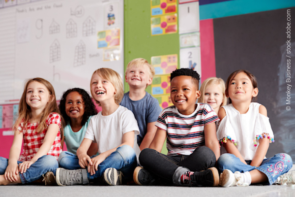 Young children sitting on a floor and smiling