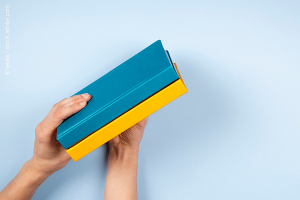 Hands holding a blue and a yellow book 