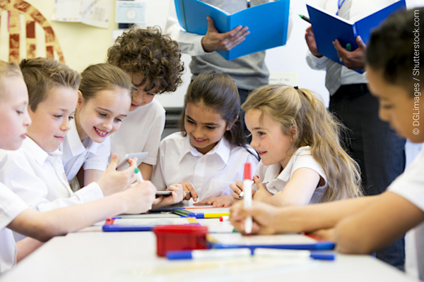Children in uniform clustered at a desk