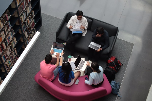 Young adult students working together in a library 