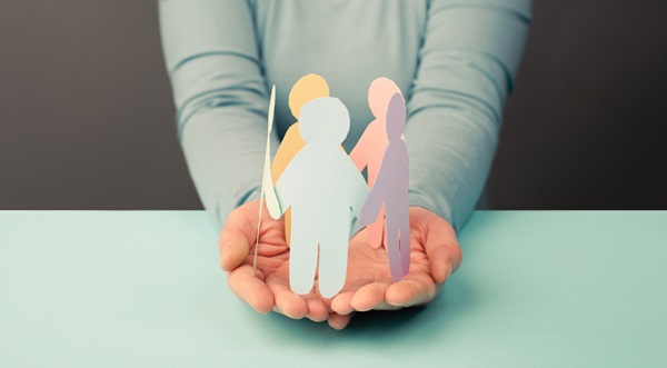Hands holding multicoloured paper cutouts of human figures