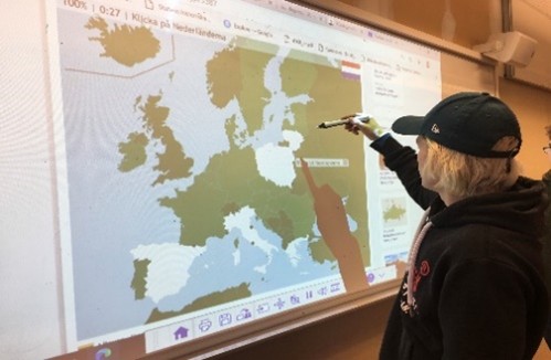 student looking at a whiteboard with a map projected