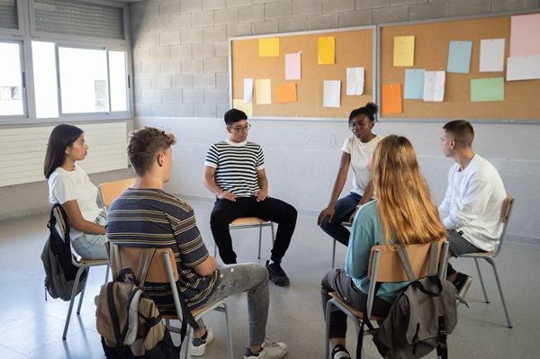 Group of students sitting in a circle in a classroom, talking about their emotions