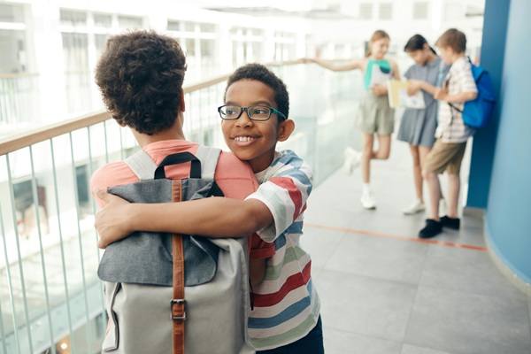 Two children embracing and smiling outside of school