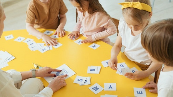 Children using letters to make words following teacher's example