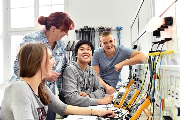 Young adults smiling together working on electronics.
