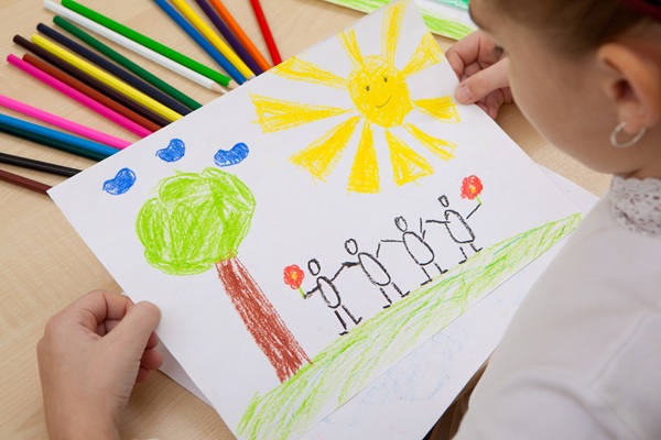 Children's pencil drawing of people, a tree, and a sun