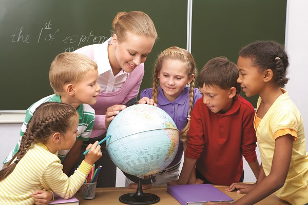 teacher and students looking at a globe in class