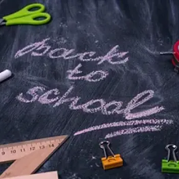 Back to school written on a blackboard with school objects around 