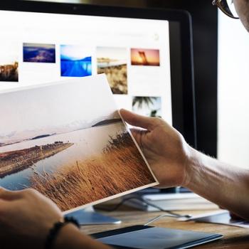 A man holding a photo in front of a screen 
