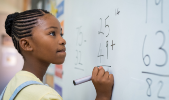 Girl solving a math addition on a whiteboard