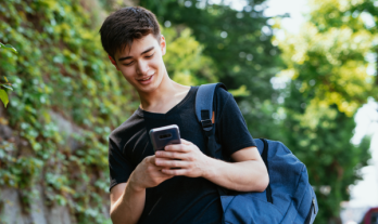 teenager with a backpack looking at his phone