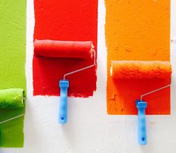 Colourful paints and paint rolls on a wall