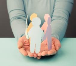 Hands holding multicoloured paper cutouts of human figures