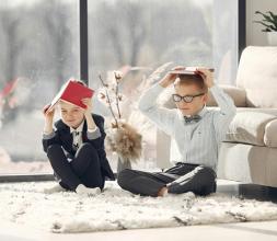 Two children sitting on floor with books on their heads 