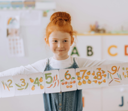 A Girl in the Classroom Holding a Paper Banner with Numbers