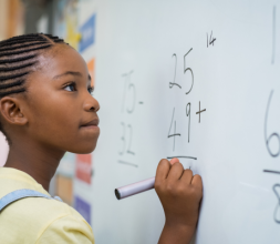 Young girl doing math equations on a blackboard