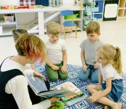 Small children with teacher reading a book