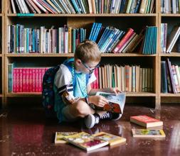 Boy sitting on library floor looking at books