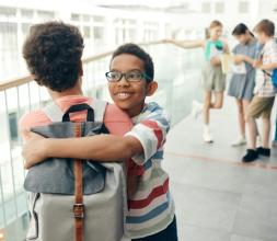Two children embracing and smiling outside of school