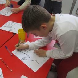 a pre-school learner adds finger prints to an outline of his hand