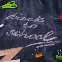 Back to school written on a blackboard with school objects around