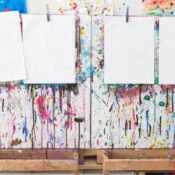 White papers hanging on a rope in front of a colorful wall