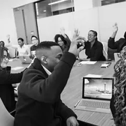 Adults sitting around the table with their hands up voting