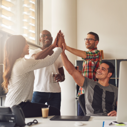Four people in an office giving each other the high five