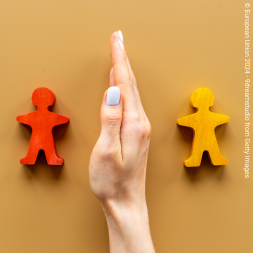 hand between little wood figures representing stickmen