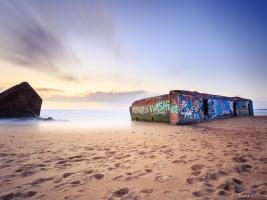 Image of the ocean in Capbreton with the remains of a graffiti-decorated German-WWII-blockhaus on the beach